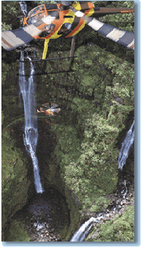 Helicopter flying over gorge with waterfall